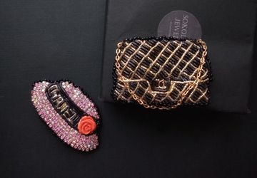 Set of brooches pink hat with a flower and a black handbag on a chain.